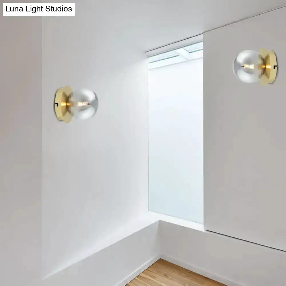 Pair of modern brass wall lamps with smoky glass globes and visible bulbs on white walls on Tampa Home & Garden Store