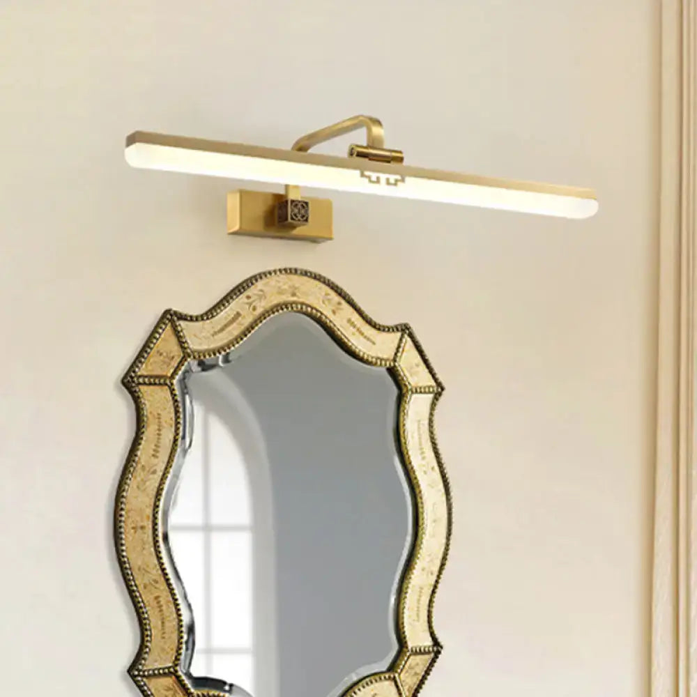 Brass wall sconce with a long white diffuser light bar above an ornate beveled mirror on Tampa Home & Garden Store