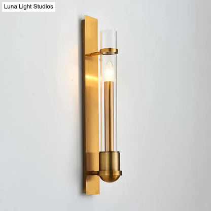 Modern brass wall sconce with clear glass cylinder shade and exposed bulb on gold backplate on Tampa Home & Garden Store