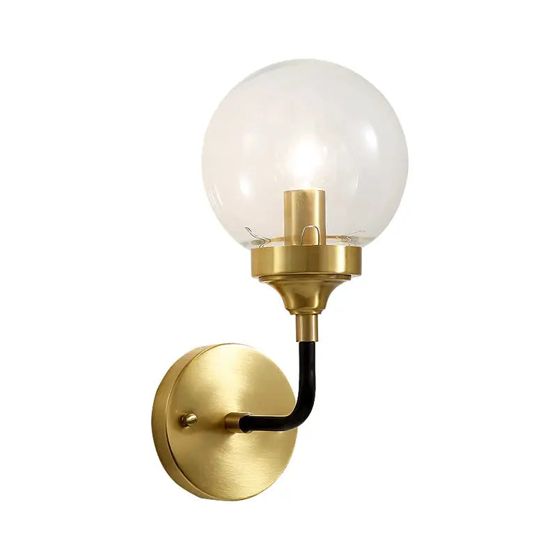 Brass curved wall sconce with clear glass globe and black arm on Tampa Home & Garden Store