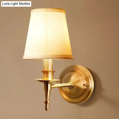 Brass fabric wall sconce with cream shade, round backplate and decorative arm on Tampa Home & Garden Store