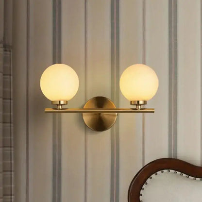 Modern brass bedroom wall sconce with dual frosted glass globes on Tampa Home & Garden Store
