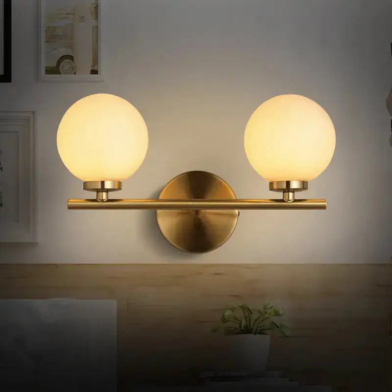 Modern brass bedroom wall sconce with two glass globe shades on Tampa Home & Garden Store