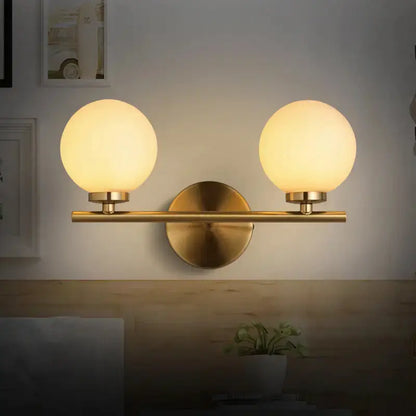 Modern brass bedroom wall sconce with two glass globe shades on Tampa Home & Garden Store