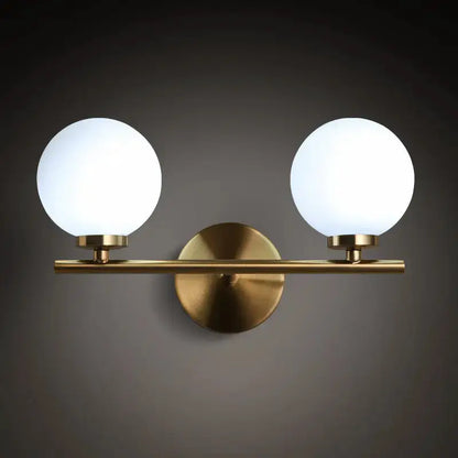 Modern brass double-globe bedroom sconce with glass shades on brass bar wall mount by Decorbites on Tampa Home & Garden Store
