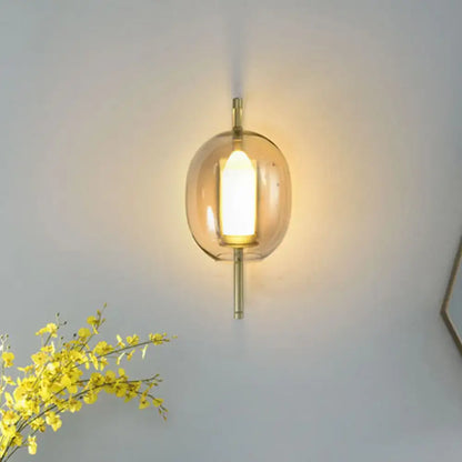 Gold oval glass hallway sconce with brass-finish stem and warm glow on Tampa Home & Garden Store
