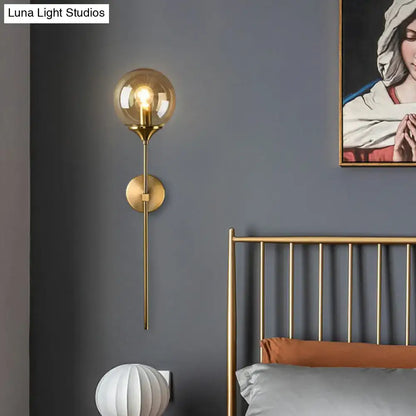 Brass pencil adjustable arm wall sconce with clear globe bulb in modern bedroom on Tampa Home & Garden Store