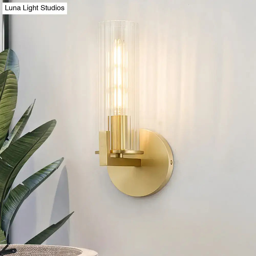 Brass wall sconce with cylindrical clear glass shade and round backplate on Tampa Home & Garden Store