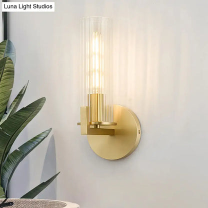 Brass wall sconce with cylindrical clear glass shade and round backplate on Tampa Home & Garden Store