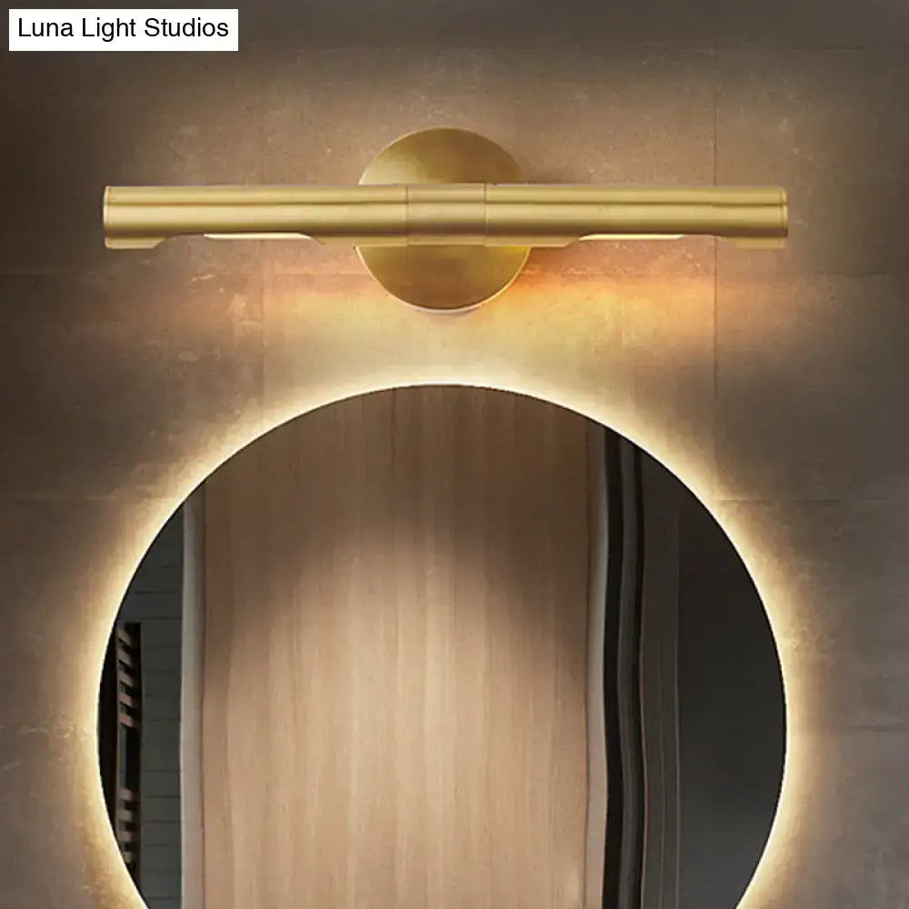 Brass tube vanity light with dual cylindrical bars over round wall mount above backlit mirror on Tampa Home & Garden Store
