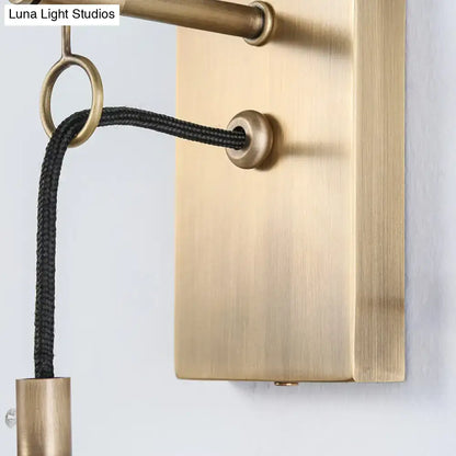 Brass wall sconce with black fabric cord through a brass ring on a brass backplate on Tampa Home & Garden Store