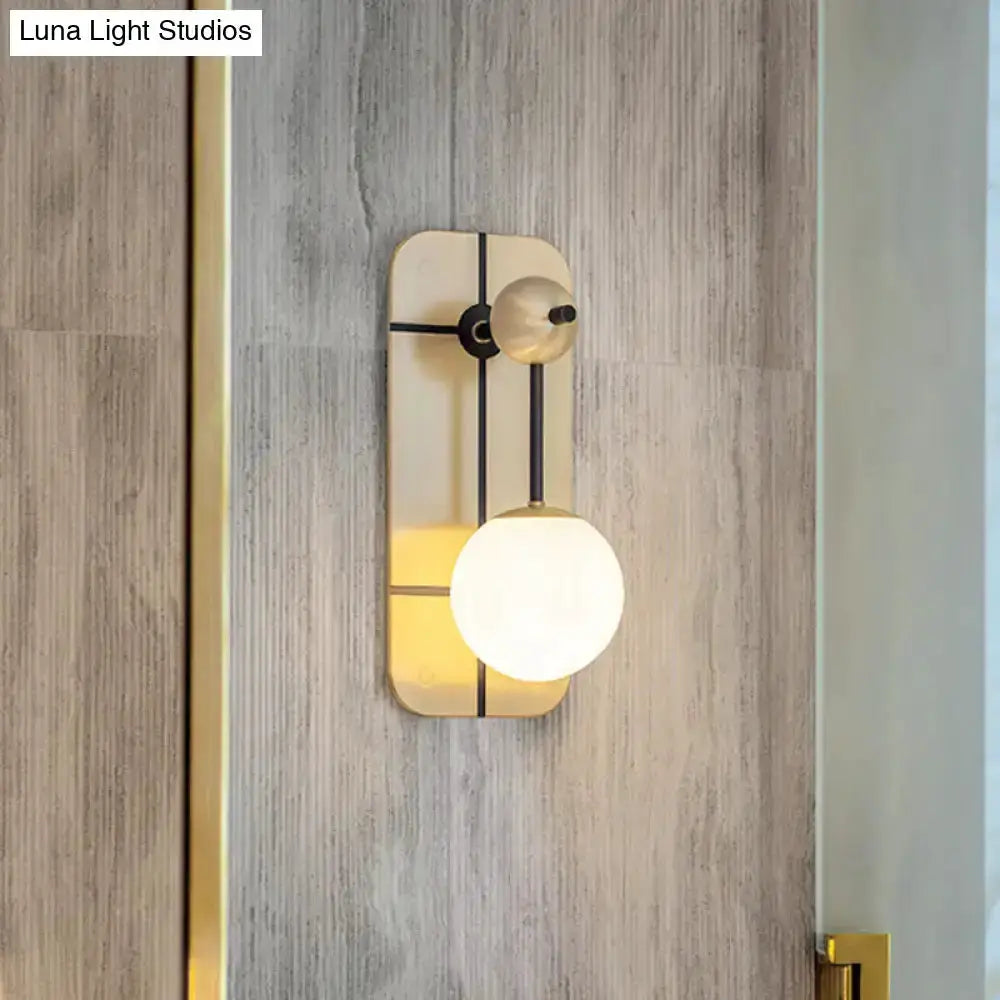 Modern brass wall sconce with opal glass globe by Decorbites on wood panel wall on Tampa Home & Garden Store