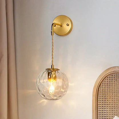 Brass water glass sconce with a clear faceted glass globe and fabric cord on Tampa Home & Garden Store