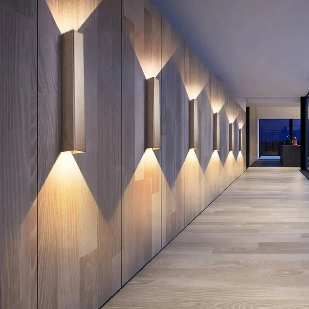 Decorbites brushed aluminum rectangular wall sconce in wood hallway emits ambient light on Tampa Home & Garden Store