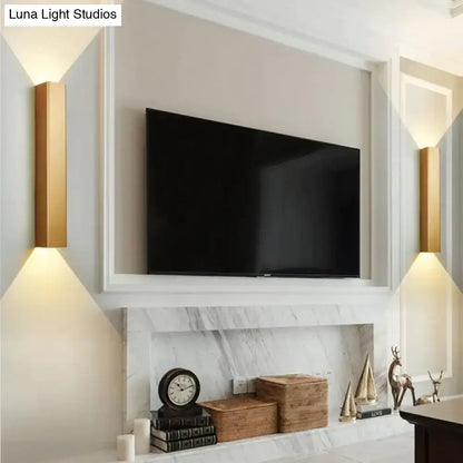 Modern brushed aluminum wall sconce pair with warm light flanking TV above marble mantel on Tampa Home & Garden Store