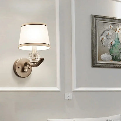 Brushed brass crystal wall sconce with curved arm and cream shade on Tampa Home & Garden Store