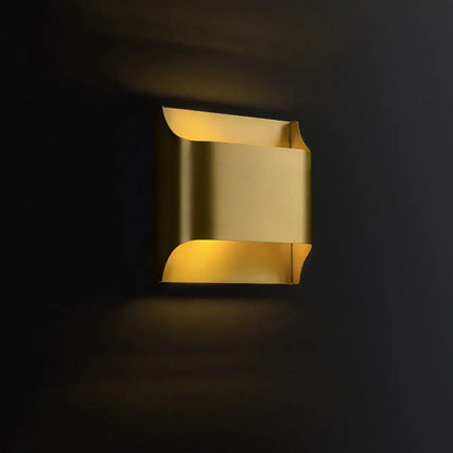Brass Geometric Wall Sconce by Decorbites, brass fixture with curved cutouts and warm glow on Tampa Home & Garden Store