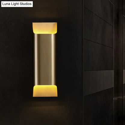 Brass geometric wall sconce with vertical cylindrical body and warm amber glow on Tampa Home & Garden Store