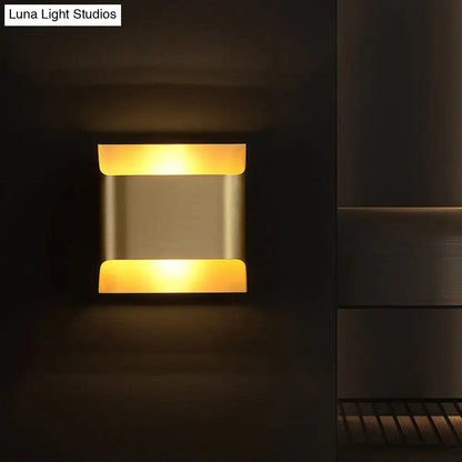 Brass geometric wall sconce with warm amber glow and modern square backplate on Tampa Home & Garden Store