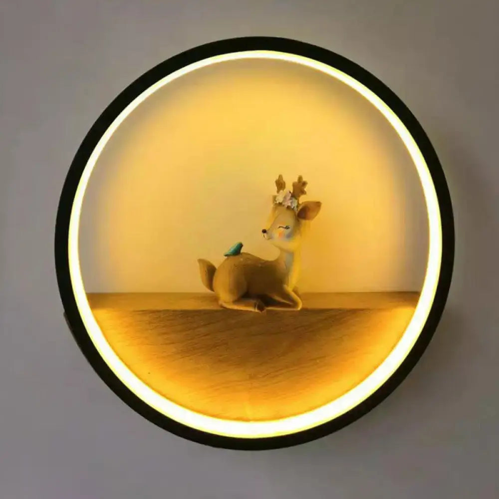 Black circular wall light with warm LED halo around a floral deer figurine and blue bird on Tampa Home & Garden Store
