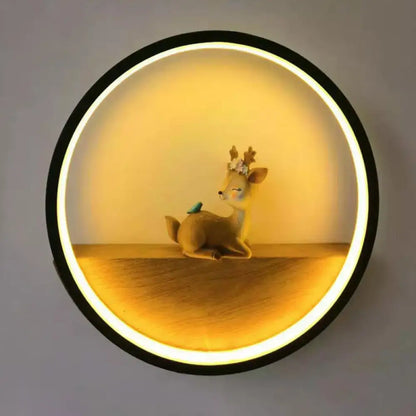 Black circular wall light with warm LED halo around a floral deer figurine and blue bird on Tampa Home & Garden Store