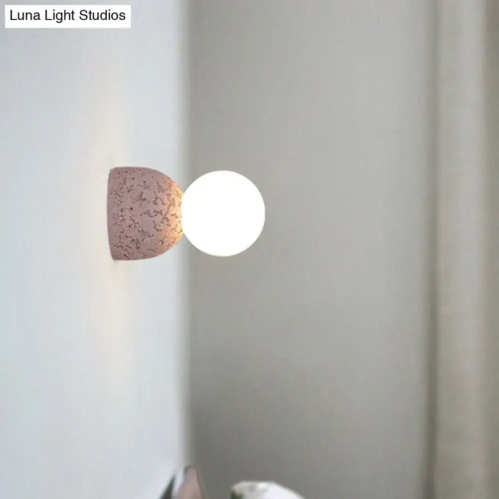 Pink concrete wall sconce with a rounded pink half-cone and white globe bulb by Decorbites on Tampa Home & Garden Store