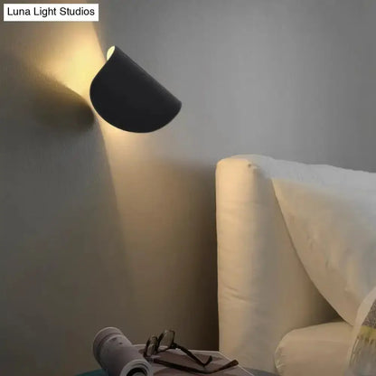 Modern curved gold wall sconce light casting warm ambient glow over a white bed on Tampa Home & Garden Store