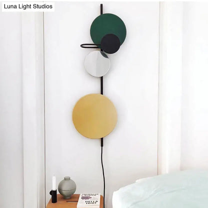 Wall sconce with vertical black rod and four discs in green, black, white, yellow; adjustable design on Tampa Home & Garden Store