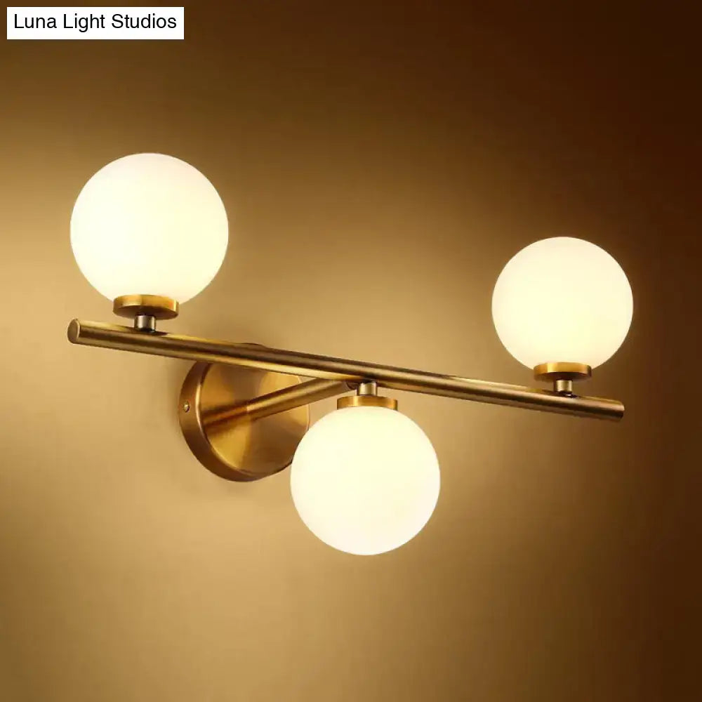 Gold modern wall sconce with three frosted glass globes on a brass horizontal bar on Tampa Home & Garden Store