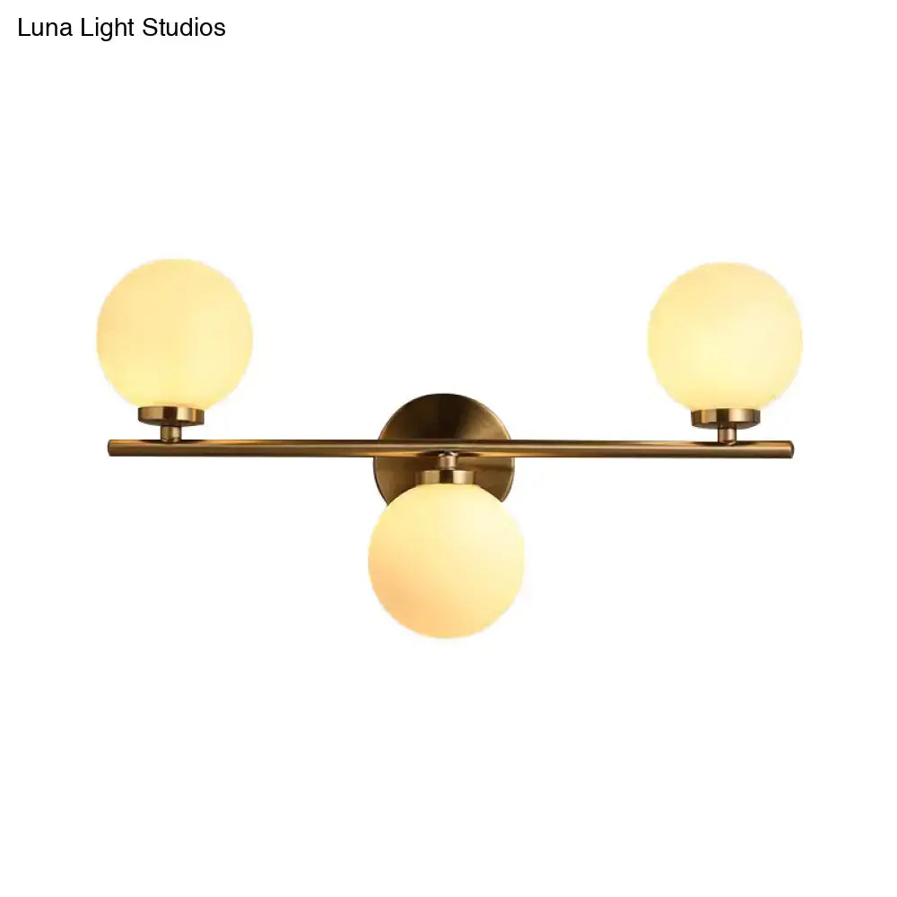 Gold modern wall sconce by Decorbites with three frosted glass globes on brass bar on Tampa Home & Garden Store