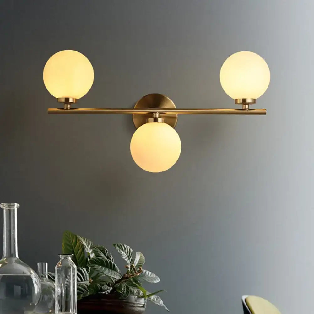 Gold modern wall sconce by Decorbites with brass bar and three frosted glass globes on Tampa Home & Garden Store