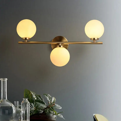 Gold modern wall sconce by Decorbites with brass bar and three frosted glass globes on Tampa Home & Garden Store