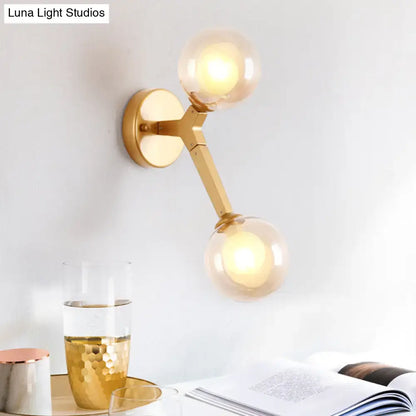 Gold amber glass wall sconce with dual globe bulbs on a gold metal arm and round backplate on Tampa Home & Garden Store