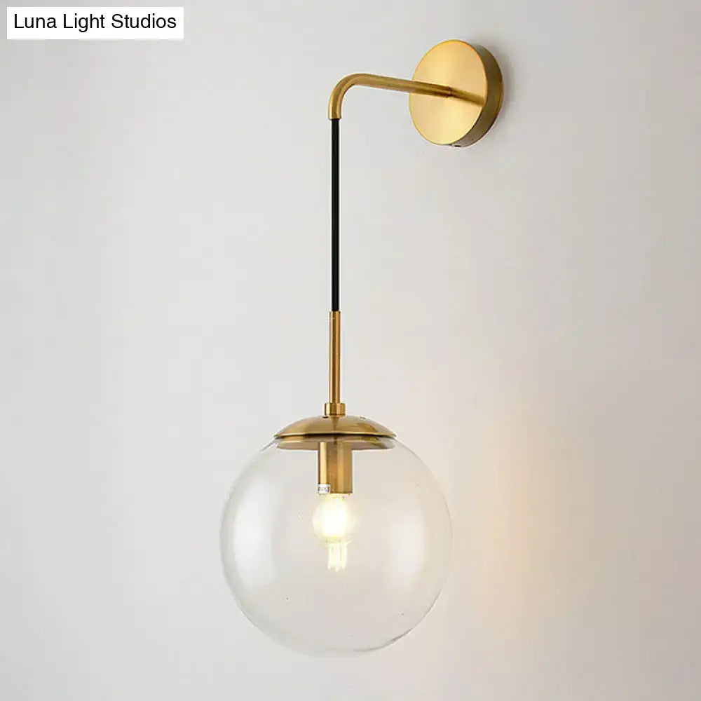 Gold and black spherical wall light sconce with brass arm and clear glass globe by Decorbites on Tampa Home & Garden Store