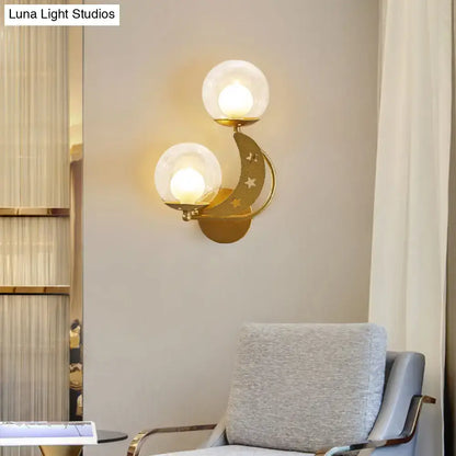 Gold ball wall sconce with dual glass globes on a crescent arm with moon and star cutouts on Tampa Home & Garden Store