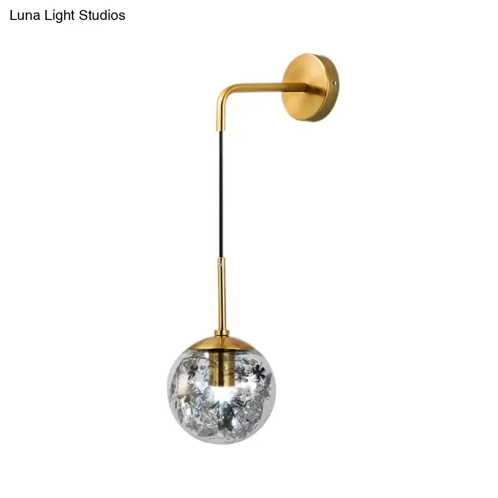 Decorbites gold glass orb wall light with curved gold arm, black cord, and glass globe on Tampa Home & Garden Store