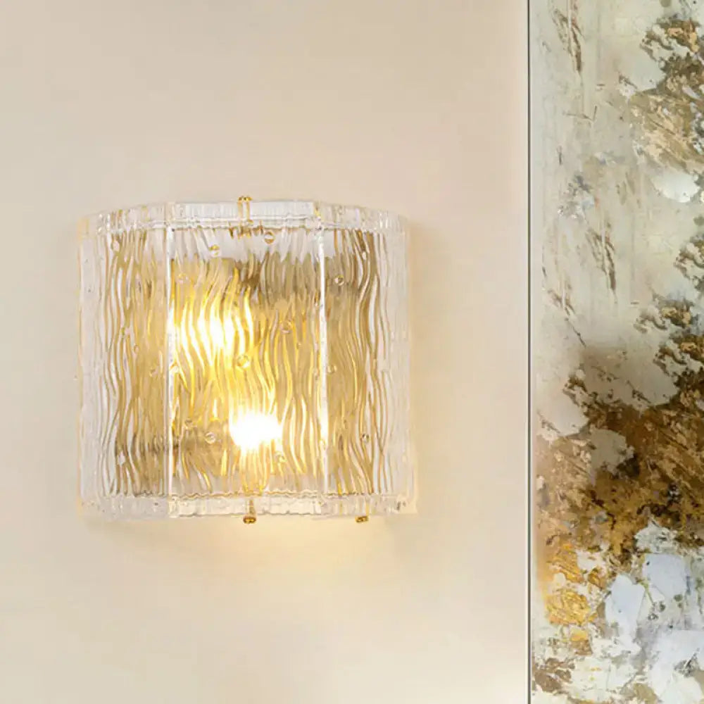 Gold ripple glass wall sconce with textured clear shade and warm glow on Tampa Home & Garden Store