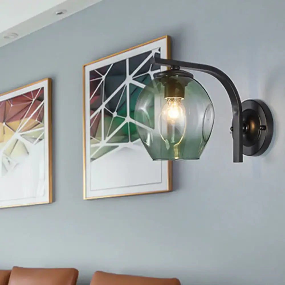 Modern gold curved arm glass wall sconce with green glass shade on backplate beside wall art on Tampa Home & Garden Store