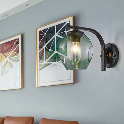 Modern gold curved arm glass wall sconce with green glass shade on backplate beside wall art on Tampa Home & Garden Store