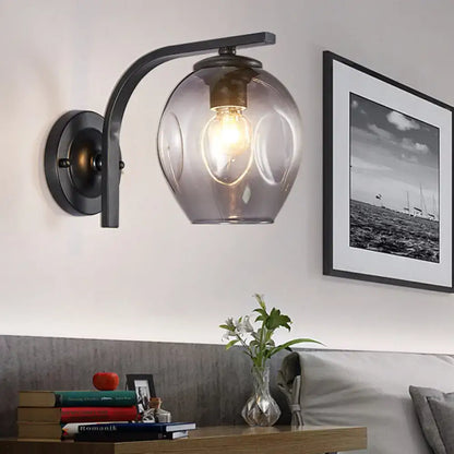 Modern curved arm glass wall sconce in dark metal with clear shade and warm bulb 1 light on Tampa Home & Garden Store