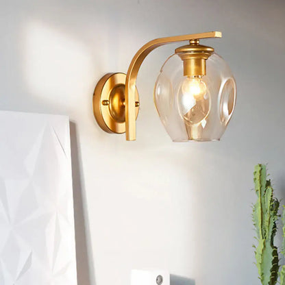 Modern gold curved-arm glass wall sconce with clear globe by Decorbites on Tampa Home & Garden Store