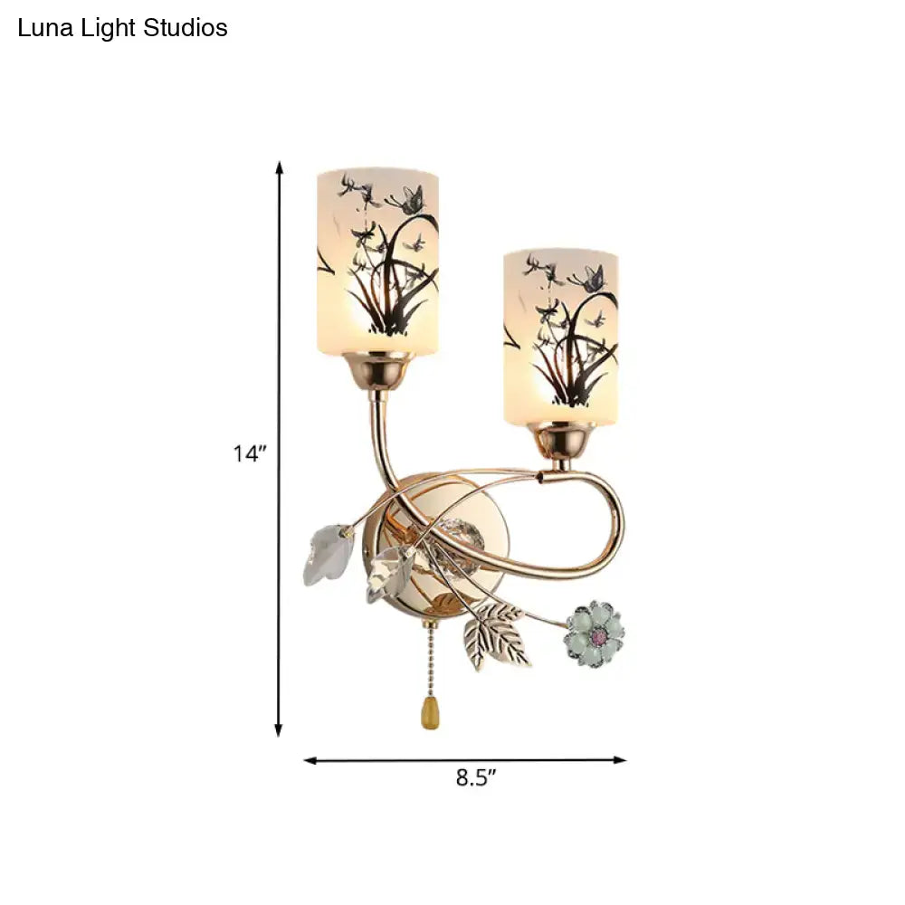 Decorbites gold cast iron two-light wall sconce with beige glass shades and leaf accents on Tampa Home & Garden Store