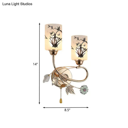 Decorbites gold cast iron two-light wall sconce with beige glass shades and leaf accents on Tampa Home & Garden Store