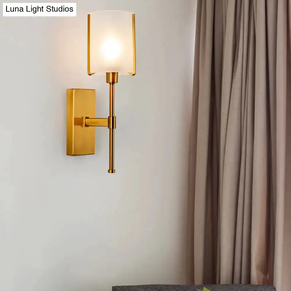 Gold frosted glass wall sconce with pencil arm and rectangular backplate, warm glow on Tampa Home & Garden Store