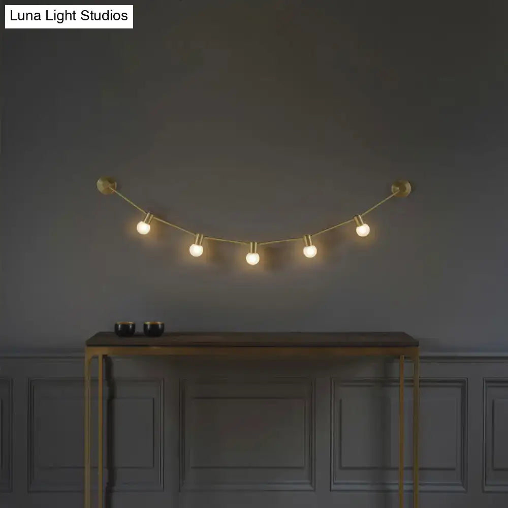Gold bubble wall light by Decorbites with five globe bulbs on brass cord above a console on Tampa Home & Garden Store