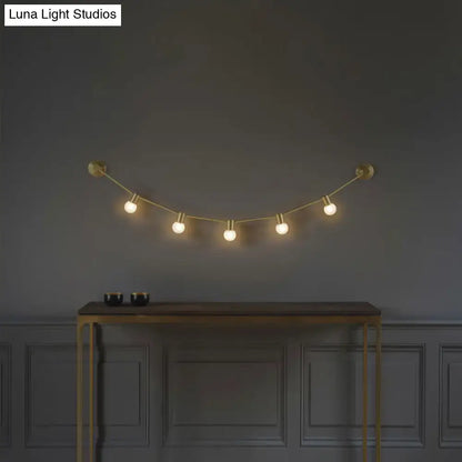 Gold bubble wall light by Decorbites with five globe bulbs on brass cord above a console on Tampa Home & Garden Store
