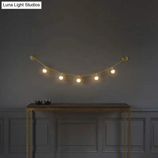 Gold bubble wall light by Decorbites with five globe bulbs on brass cord above a console on Tampa Home & Garden Store