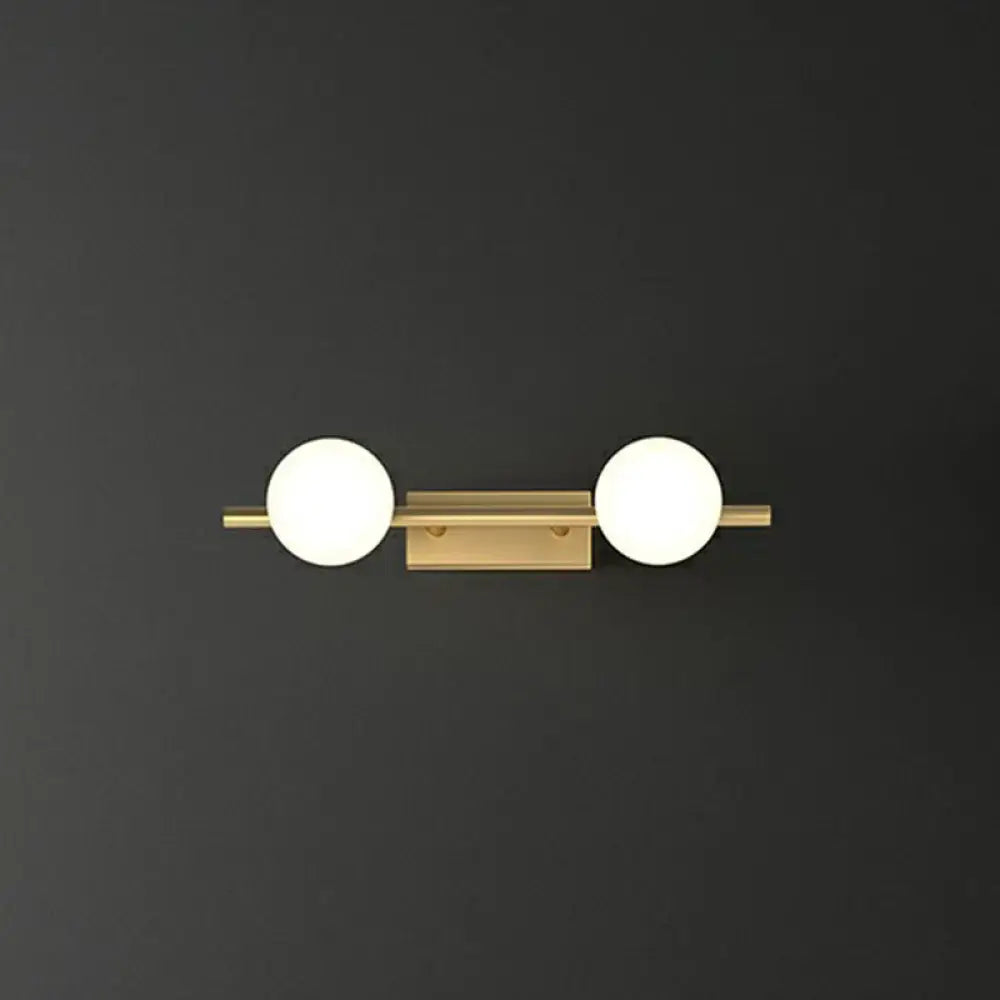 Gold milky glass two-light bathroom sconce on brass bar against dark wall on Tampa Home & Garden Store