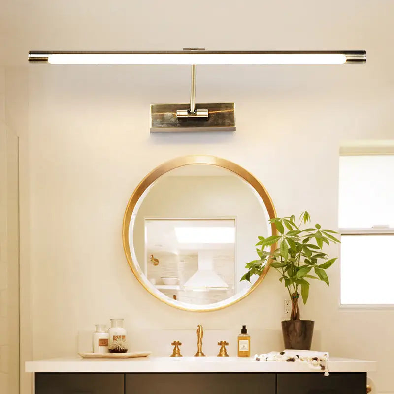 Modern gold minimalist metal LED sconce above a round gold-framed bathroom mirror on Tampa Home & Garden Store