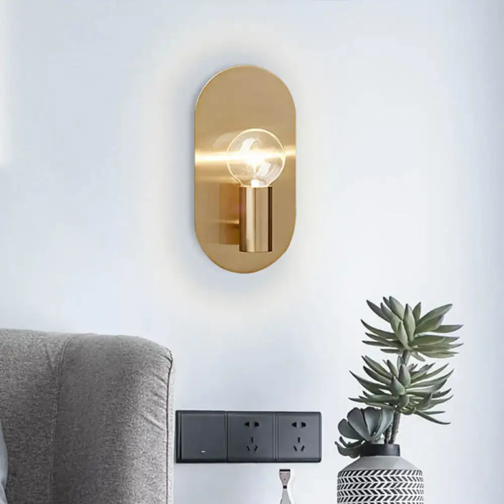 Gold metal bare bulb sconce by Decorbites with a glowing bulb mounted on a white wall on Tampa Home & Garden Store